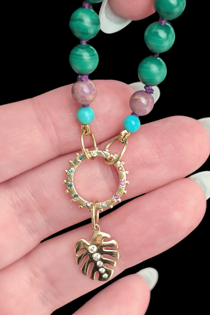 Delphine Leymarie Boheme Provence beads with rainbow charm holder connector and gold Monstera charm from Beaumont Jewelry Collective.