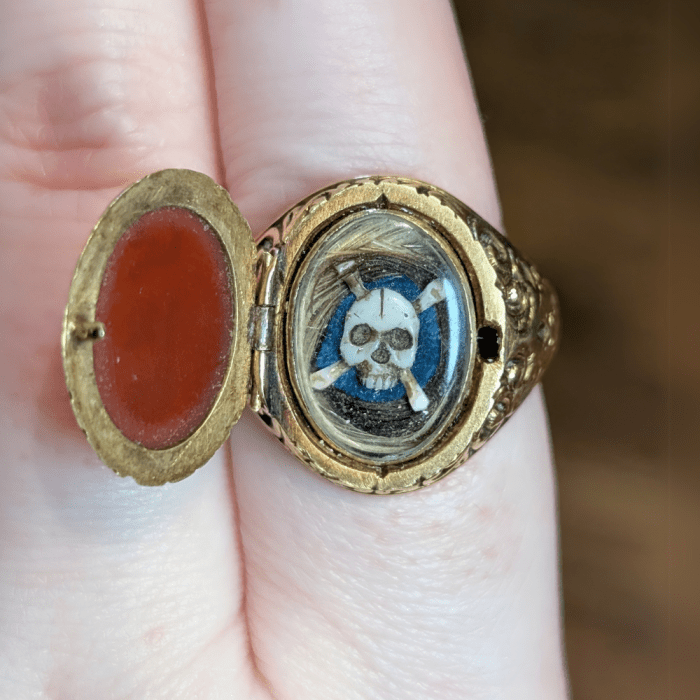 This mourning ring opens to reveal a hidden compartment with hair and a skull and crossbones! From Sandy Jacobs Antiques.